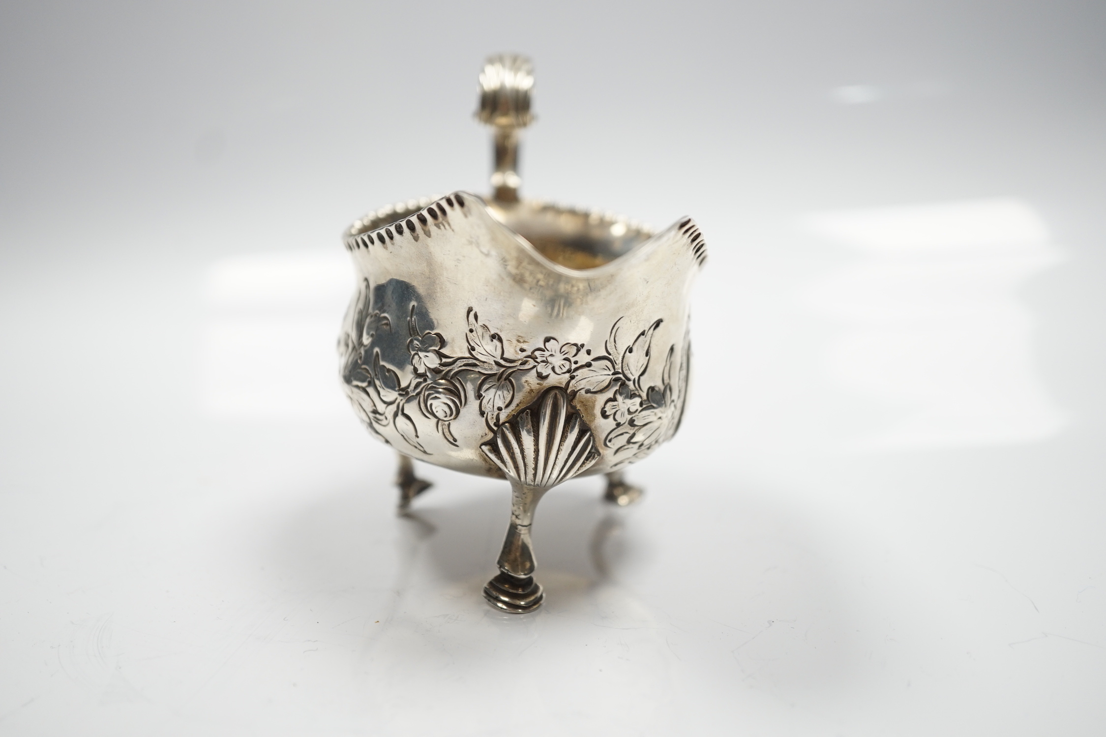 A George III silver sauce boat, with flying scroll handled and later embossed decoration, maker T?, London, 1776, length 15.5cm, 5.75oz.